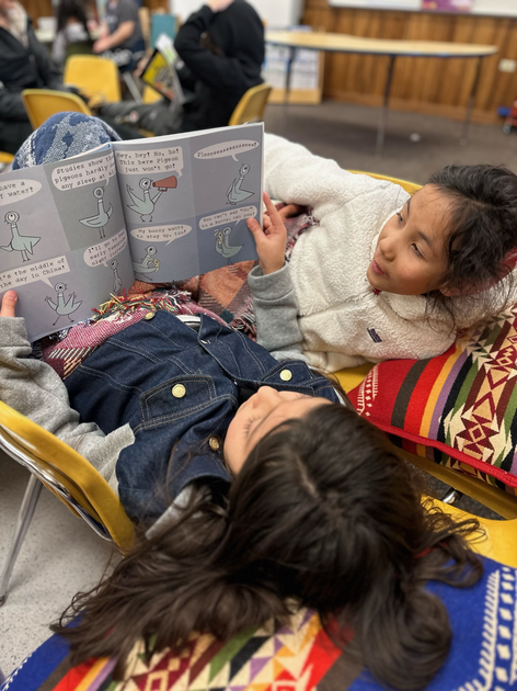  Two children reading a book together.