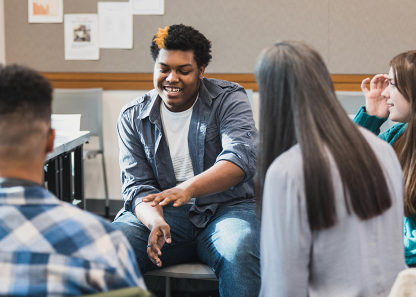Young adults sitting in a circle conversing