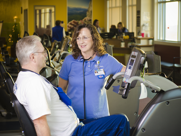 Nurse speaking with a patient on an exercise bike.