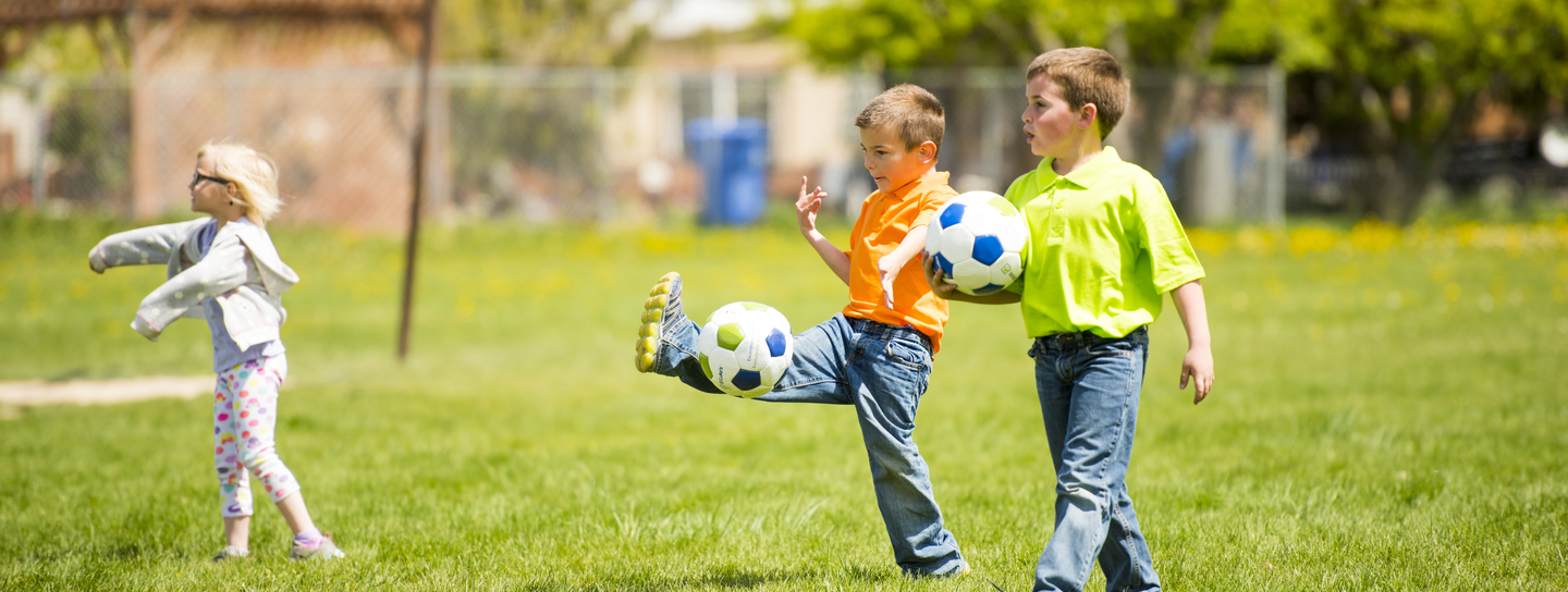 Children kick soccerballs in a field