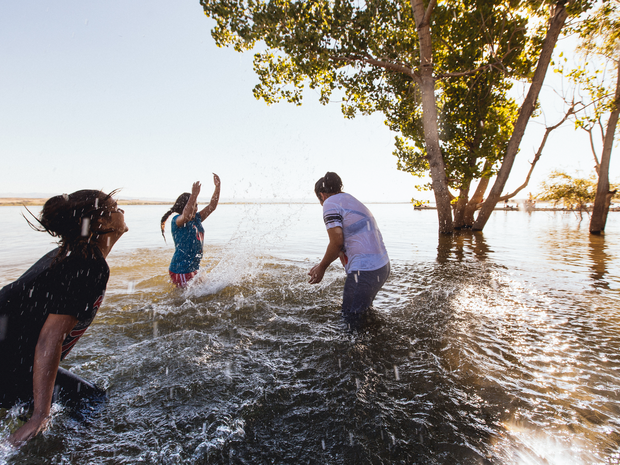 Three people standing in the lake splashing water.