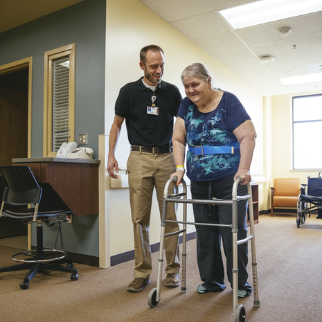 Older woman smiles while being help up for support.