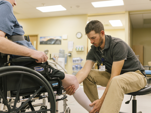 Physical therapist working with patient in wheel cha