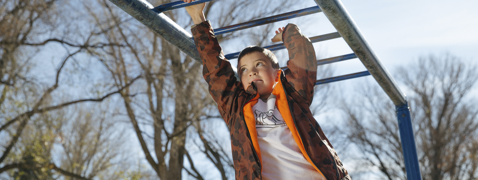 Boy playing on monkey bars at playground.