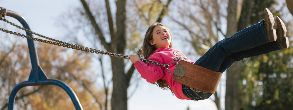 Girl smiles while swinging outdoors.