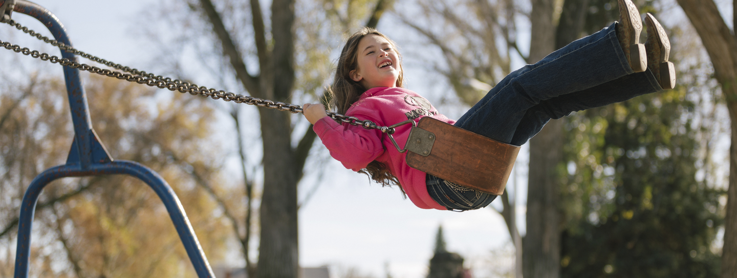 Girl smiles while swinging outdoors.