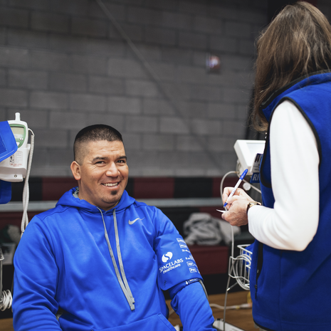 Man smiles while getting blood pressure drawn at health event.