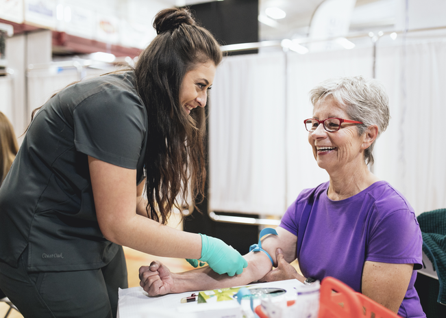 Woman smiles while getting blood drawn at community blood drive.