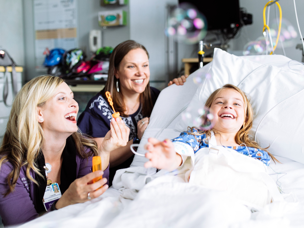 Child life specialists blow bubbles with a patient