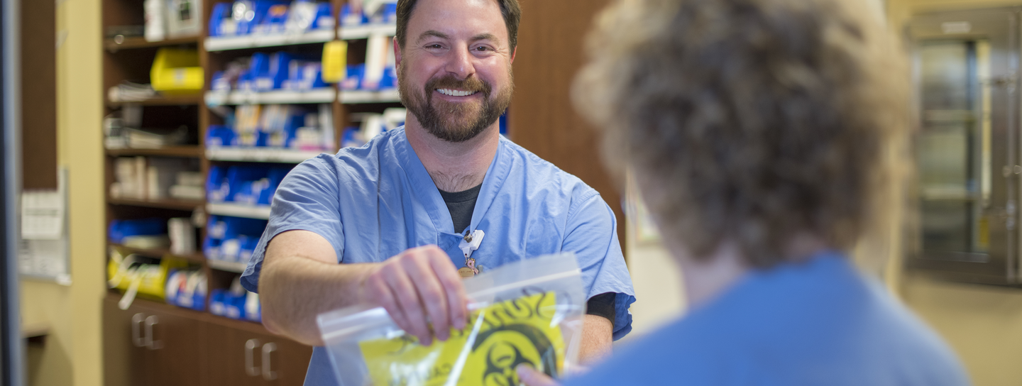 Pharmacy technician handing a prescription to a patient.