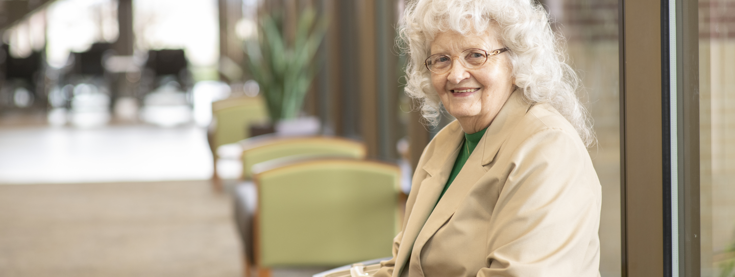 An older patient sits in the waiting room, smiling for the camera
