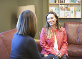 A woman wearing a pink jacket speaking with a social worker