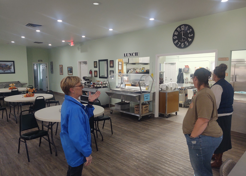 Group of people standing in large room of senior center