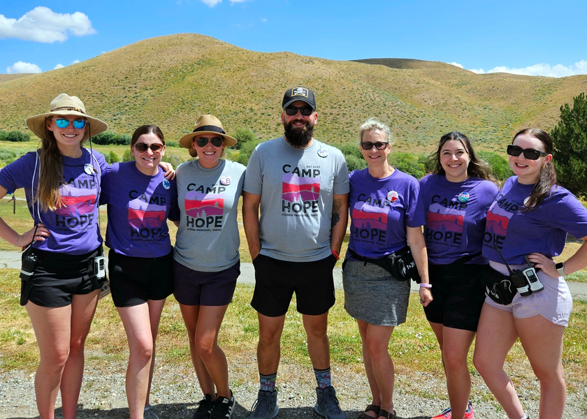 People in purple and grey shirts stand outside