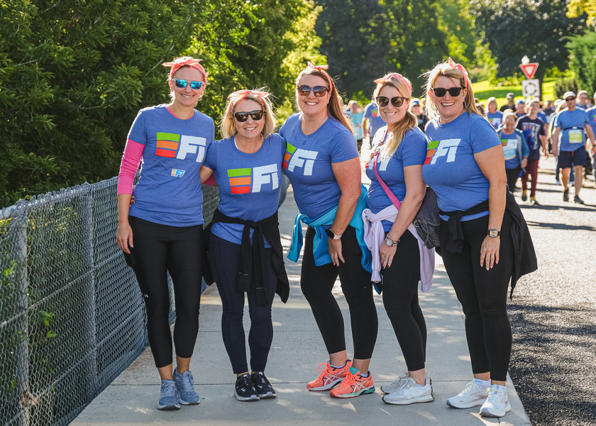 Five women in matching race tshirts smile at camera