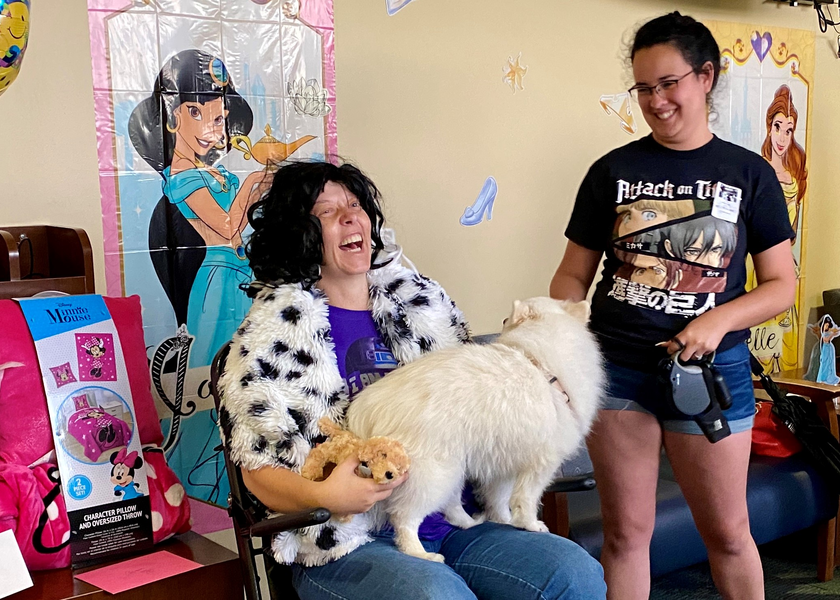 Two women laughing, one holding a white dog