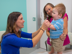 Pediatric provider works with smiling toddler in clinic.
