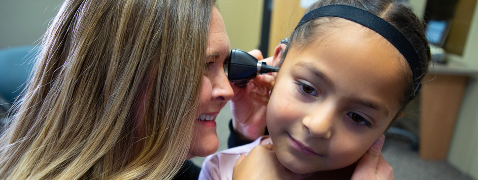 A baby with their finger near their ear