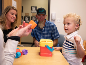 A little boy with a hearing aid playing with colorful blocks. 