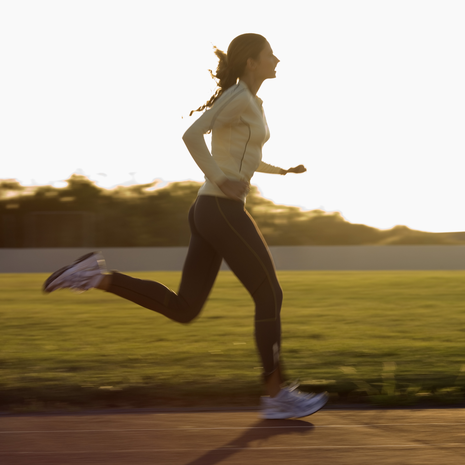 A woman in a college jersey running on a track. 
