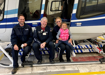 Young girl sits on helicopter with medical staff