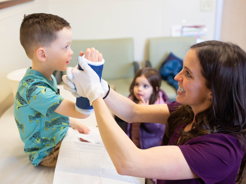  Dr. Krysten Bell smiles with a young boy in a cast
