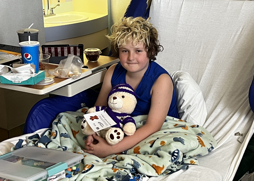  Young child in hospital bed holds teddy bear