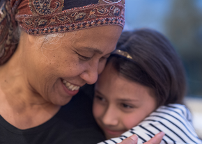 Cancer patient hugs child while smiling