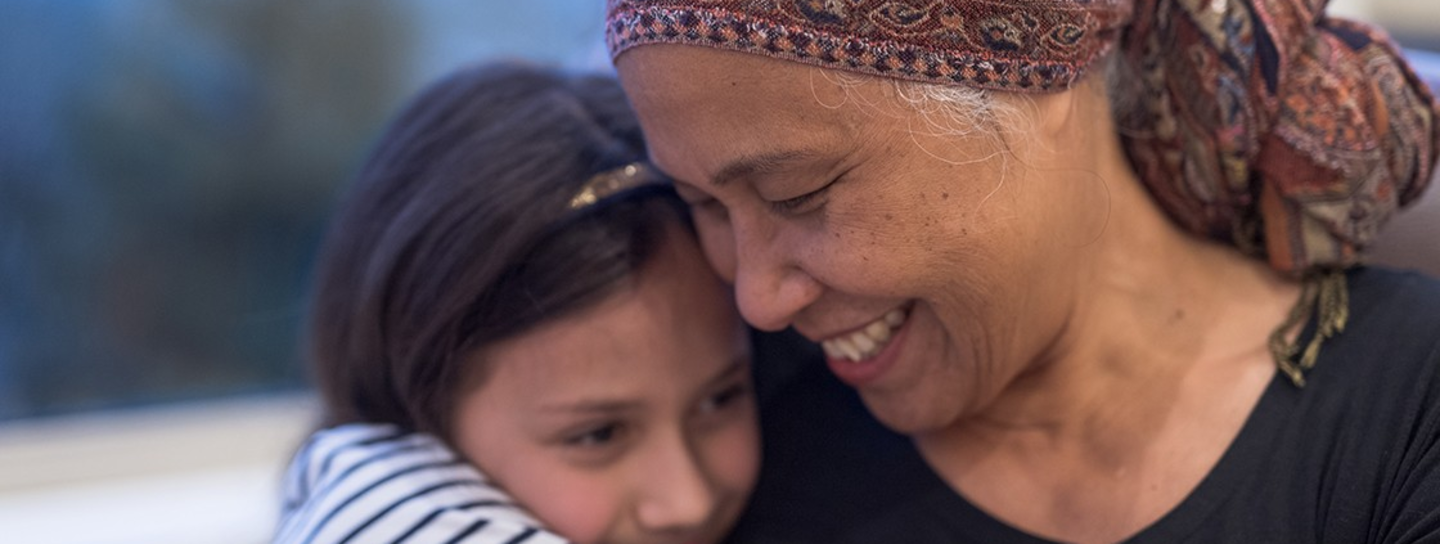 A woman in a headscarf embraces a child with a smile