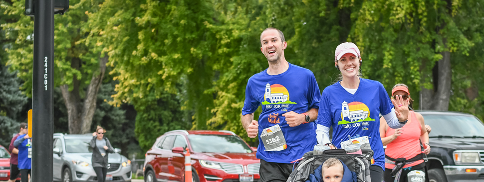 Grandparents play with their grandson outside at sunset.
