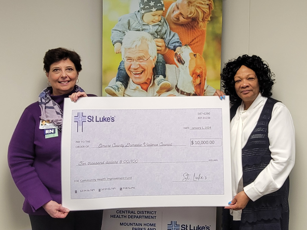 Two employees hold up a $10,00 0 check to St. Luke’s