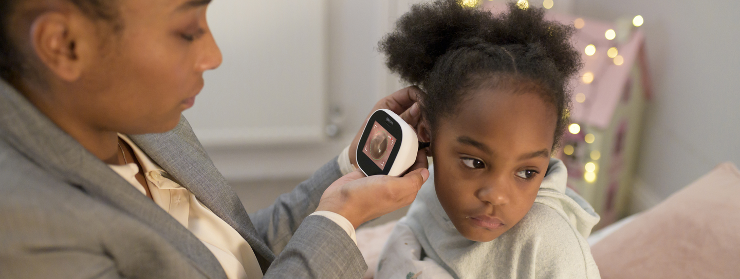 mom using a TytoCare device to check her daughter's ear