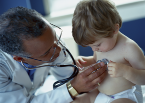 A doctor holds a stethoscope to the chest of a baby wearing a diaper
