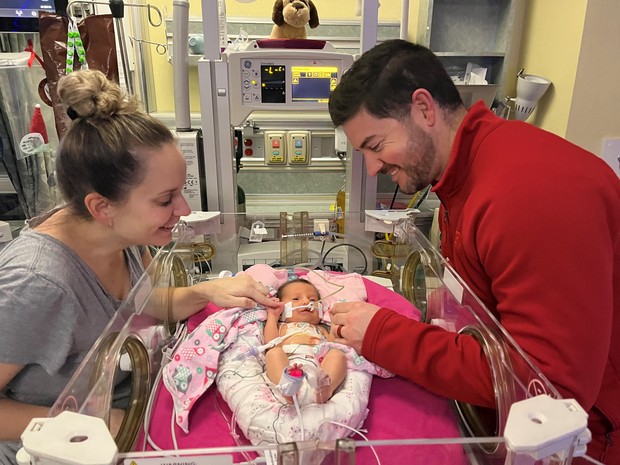 The Fuller's smile at their daughter in the NICU.