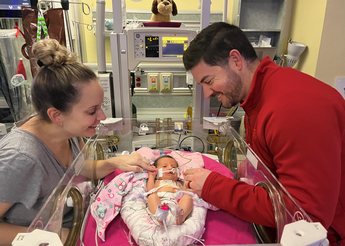 The Fuller's smile at their daughter in the NICU.