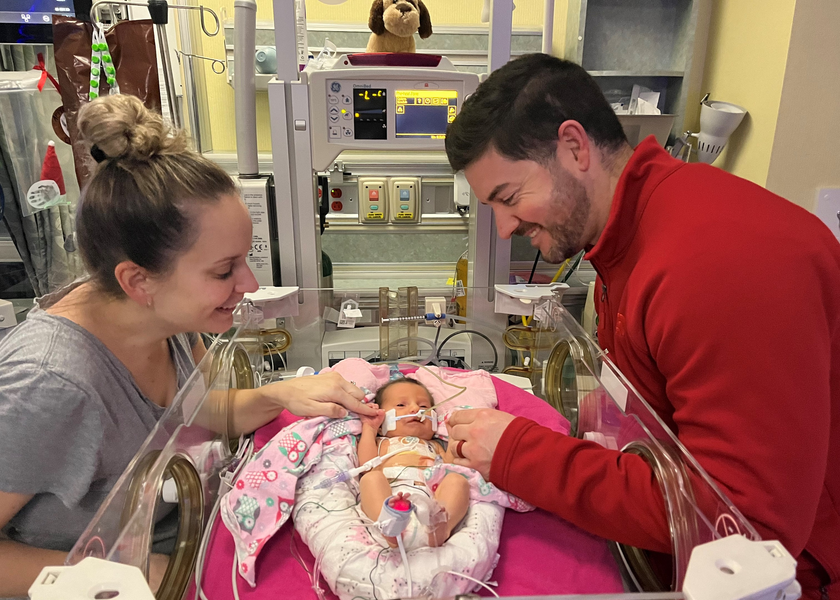 The Fuller's smile at their daughter in the NICU.