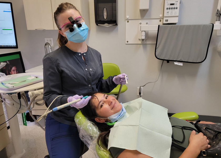  Dental staffer stands over woman in dental chair