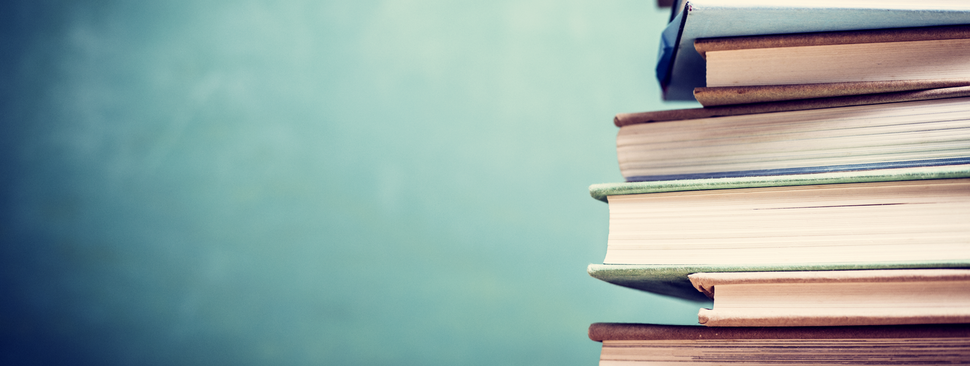Elderly man reading a book in a hospital room.