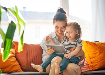 Mom with daughter on lap on virtual call.