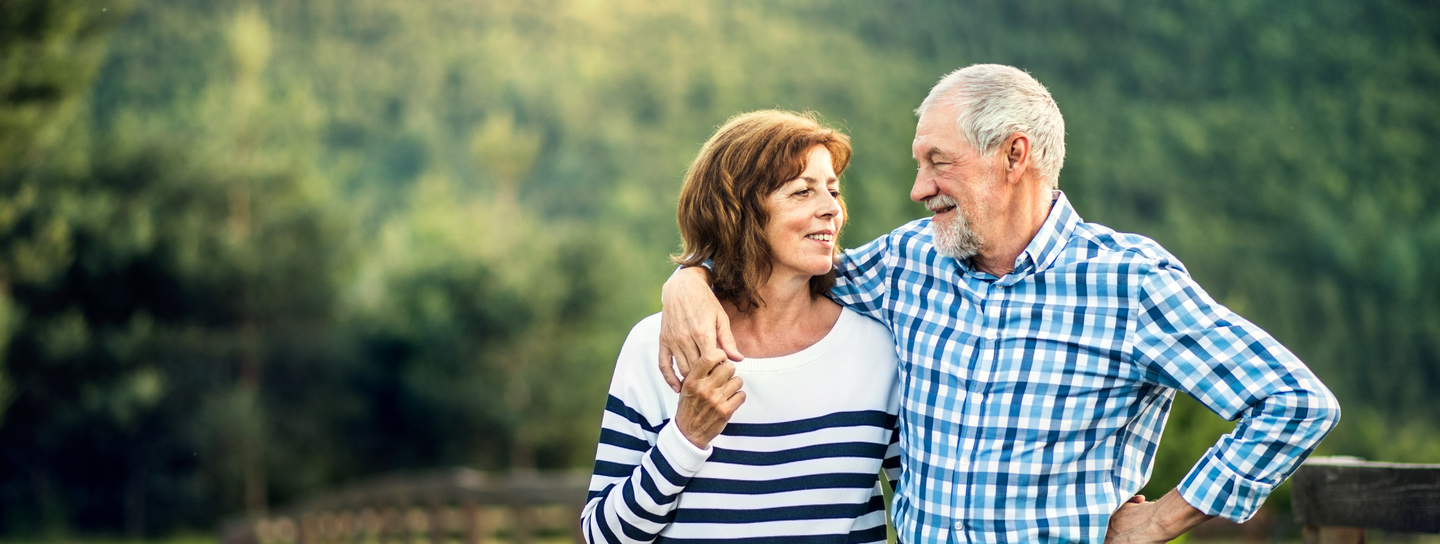 A couple stands on a gravel road, looking into each others eyes
