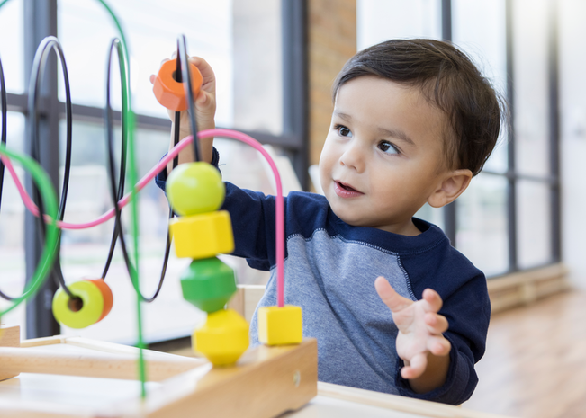 A young boy plays with a sliding block toy
