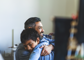 A father hugs his son with a smile