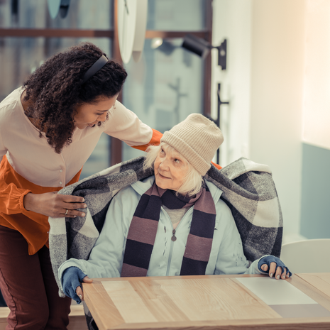 Woman offering an elderly woman a warm blanket