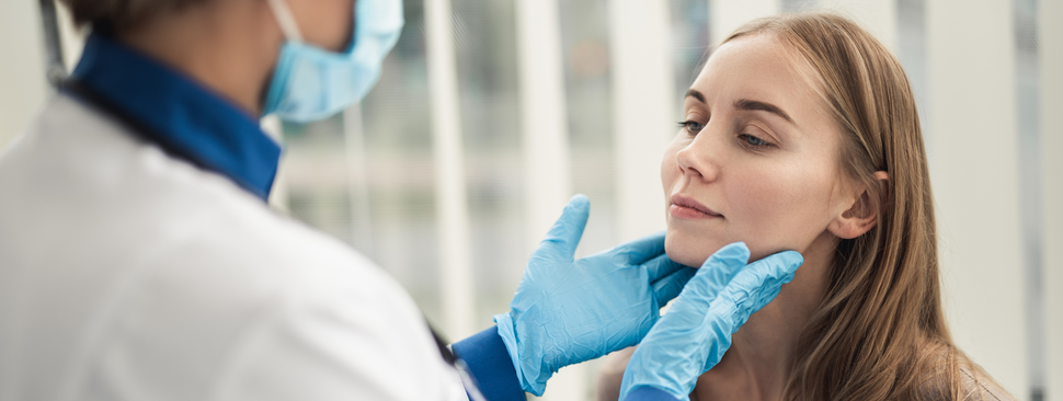 Young woman getting throat examined by doctor