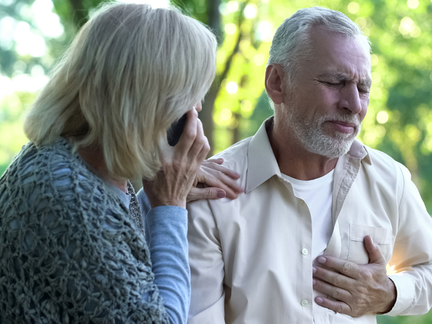 Woman on phone with man holding his chest in pain