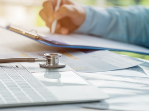 A medical professional works on a laptop