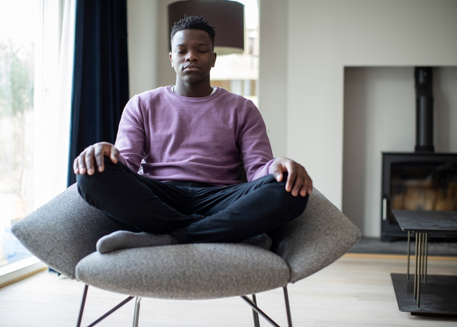 A man sits cross-legged as he meditates.
