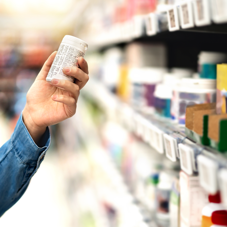 man looking at a vitamin bottle in a store