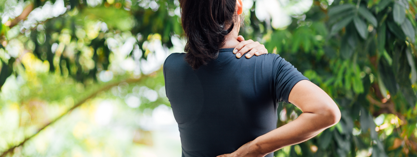 A woman faces away from the camera as a hand cradles between her neck and shoulder