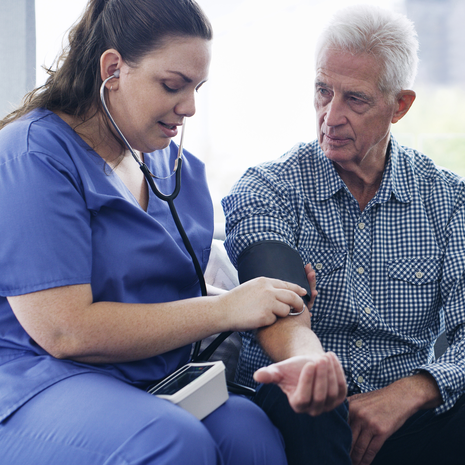 Older man having his blood pressure checked in his home by a home health professional